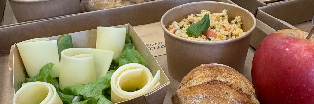 Plateaux repas en cours de montage : salade et fromage, taboulé à la menthe, pain et pomme